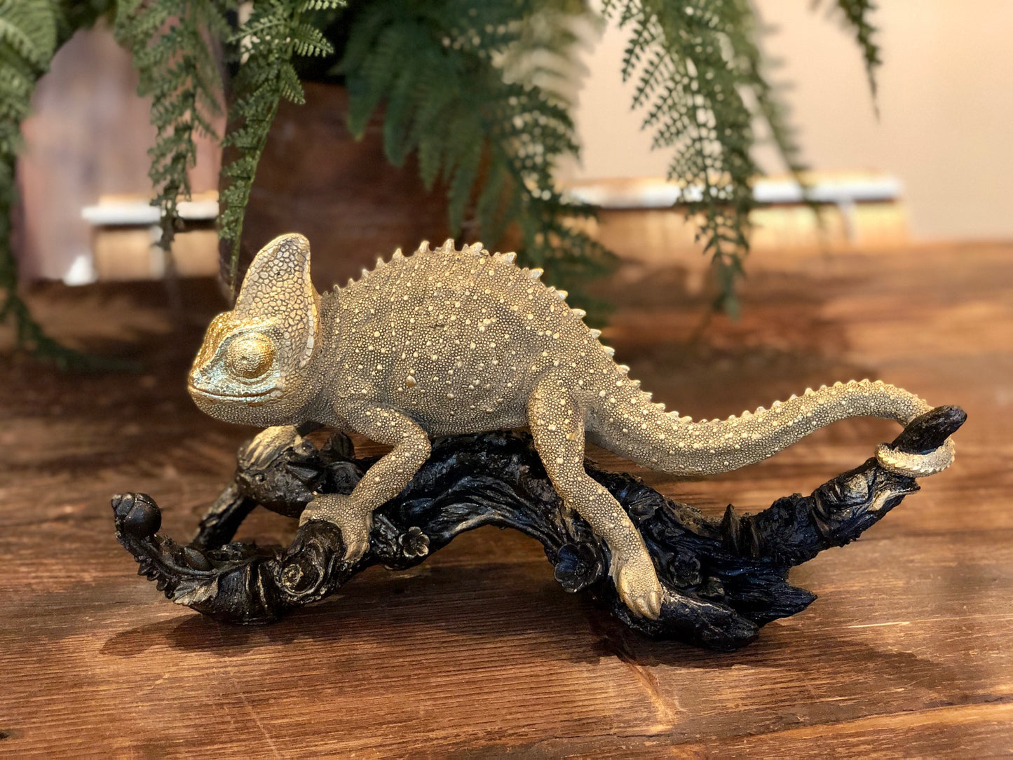 Guldfärgad Kameleont på svart gren